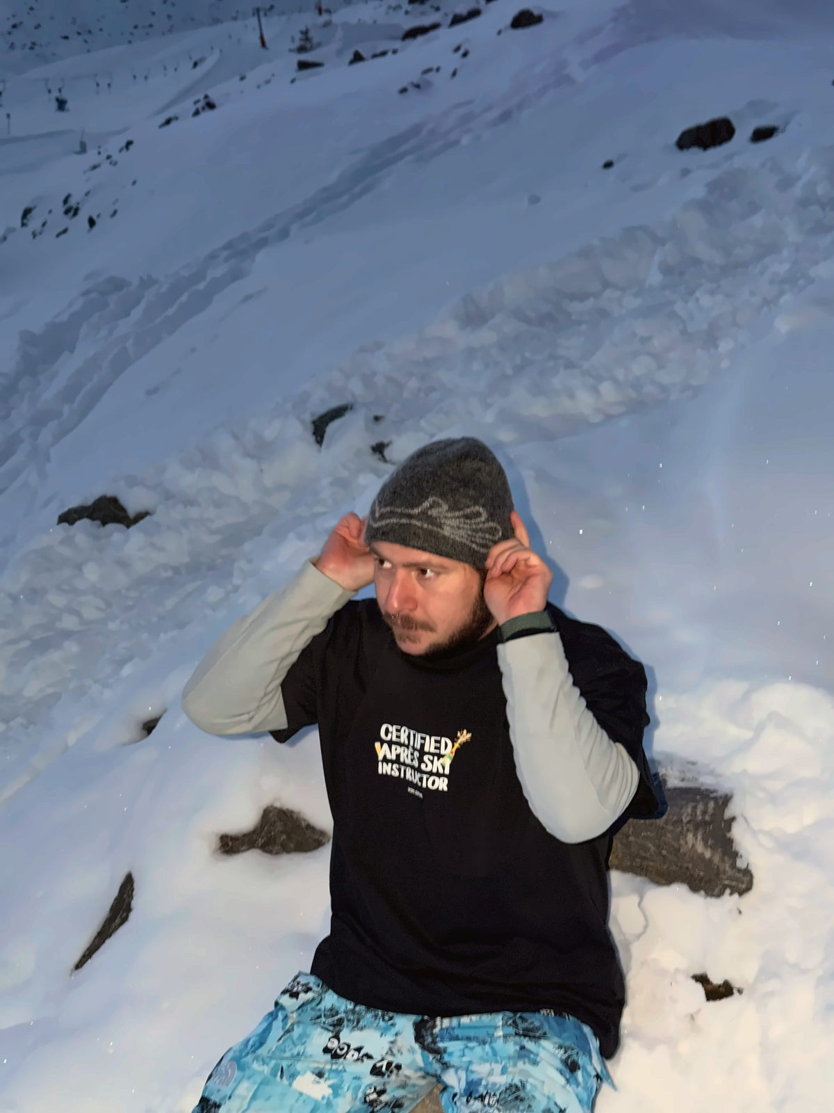 Von Alpen "Certified Après Ski Instructor" tee, sitting in the snow at dusk