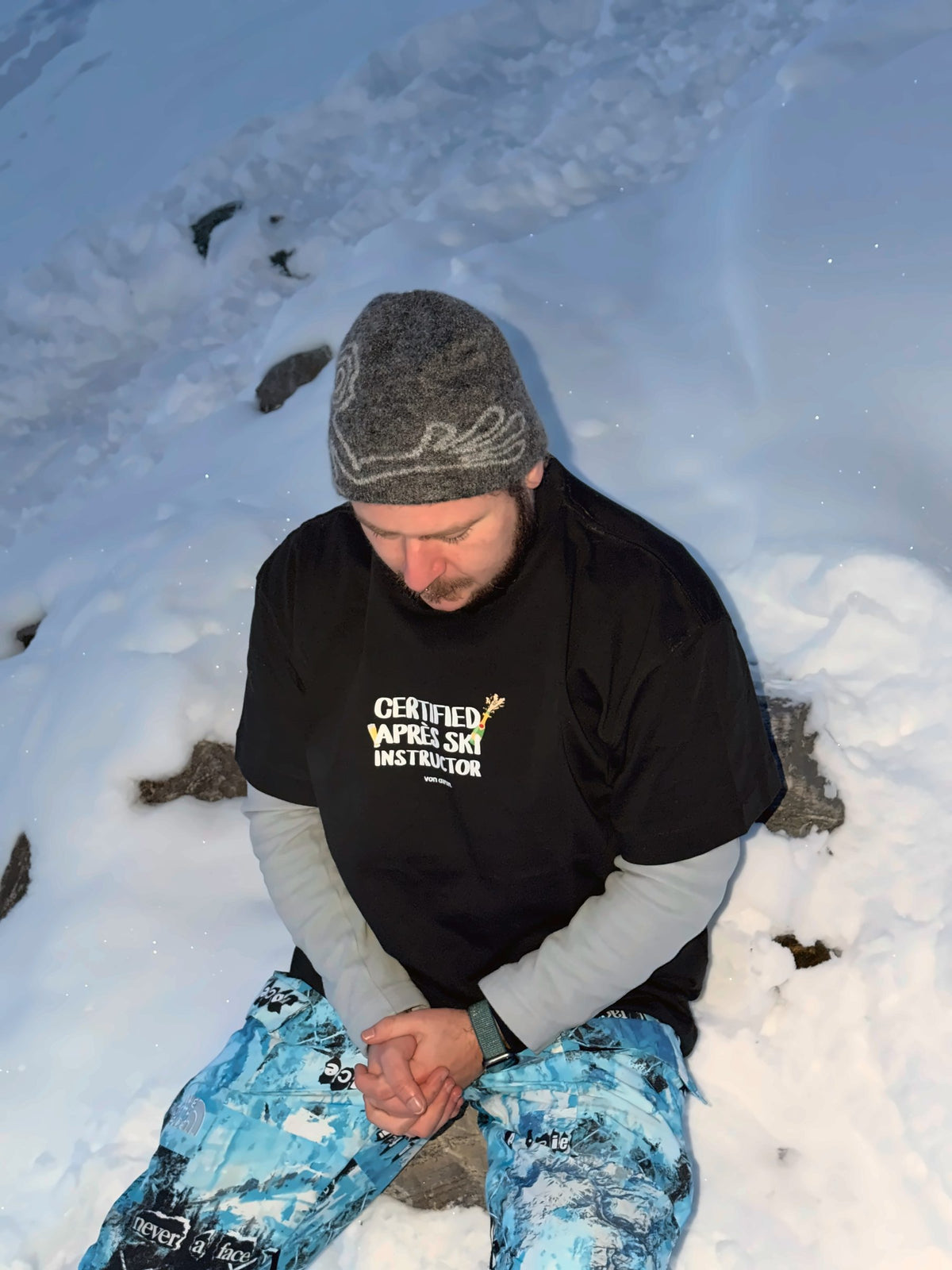 Von Alpen "Certified Après Ski Instructor" tee in the snow at dusk, close-up